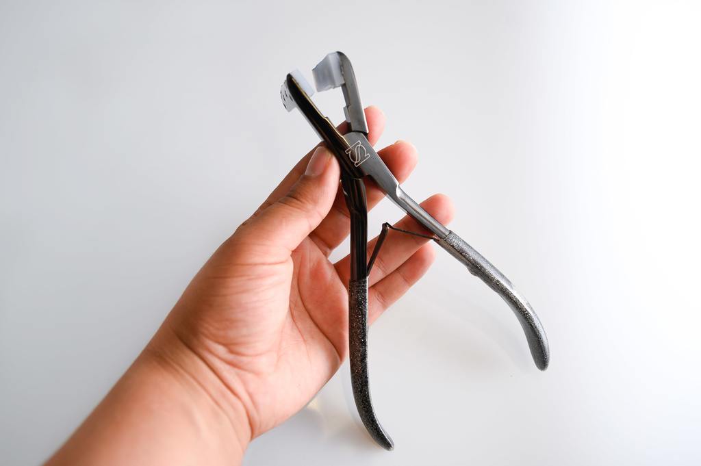 Hair Extension Tape Application Press Pliers in hand on a white canvas